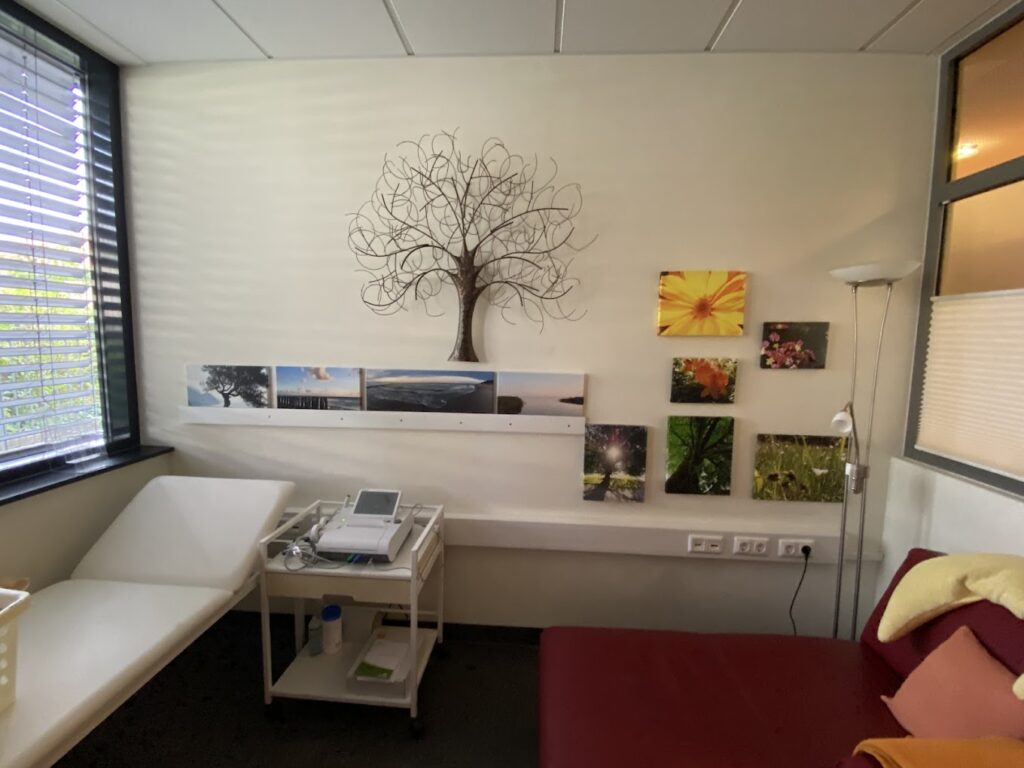 Praxisraum mit einer Liege und dekorativen Bildern an der Wand